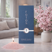 FOTON pearlled candle packaging with a lit candle and flowers in the background