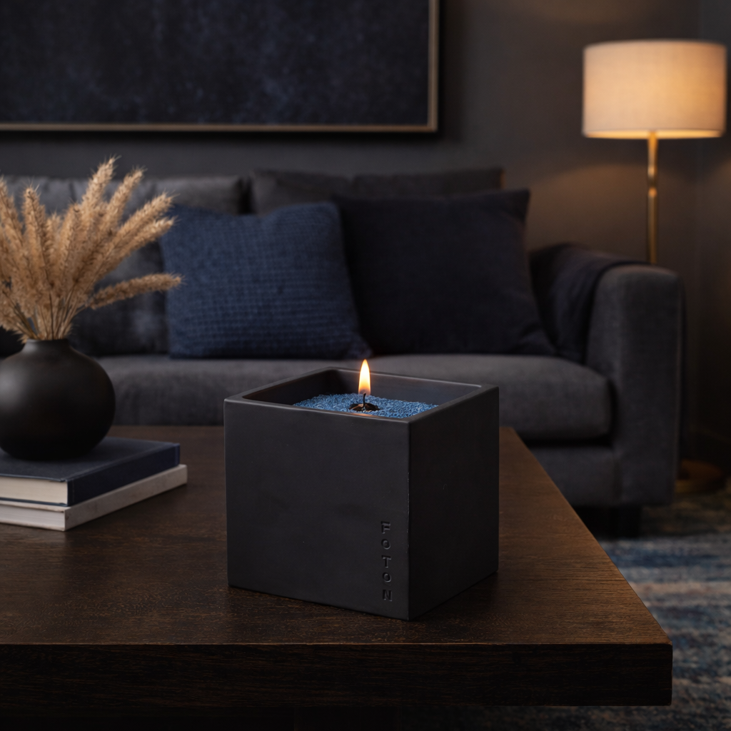 Cozy lifestyle image of the black Le Cube candle glowing on a coffee table in a softly lit living room, surrounded by warm textures and modern décor to create an intimate, relaxing evening ambiance.