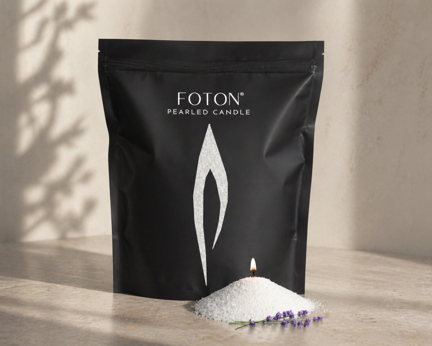 Black Foton Pearled Candle grande bag displayed on a neutral surface next to a small mound of white wax pearls with a lit wick and lavender, with soft shadows and minimal styling.