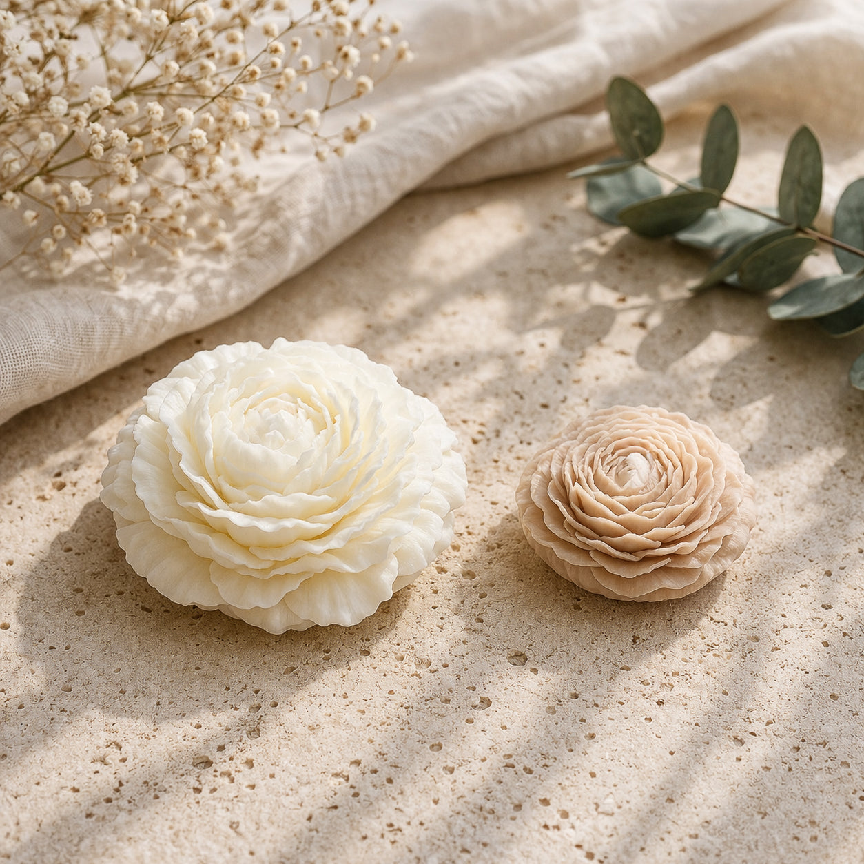 Product image of two flower-shaped wax accessories in soft ivory and blush tones, designed with layered petal detailing for an elegant, decorative look.