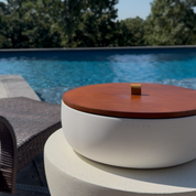 Oversized white Luxe Concrete Bowl with the matching wooden lid in place, displayed poolside. The image emphasizes the clean, modern design and the protective lid for outdoor use.