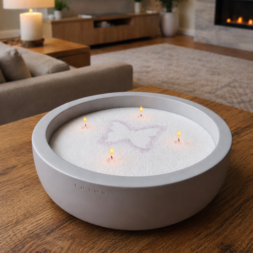 Large FOTON candle in a round charcoal Luxe concrete vessel, filled with white pearled wax and featuring four evenly spaced lit wicks. A subtle butterfly stencil design is visible across the surface. 