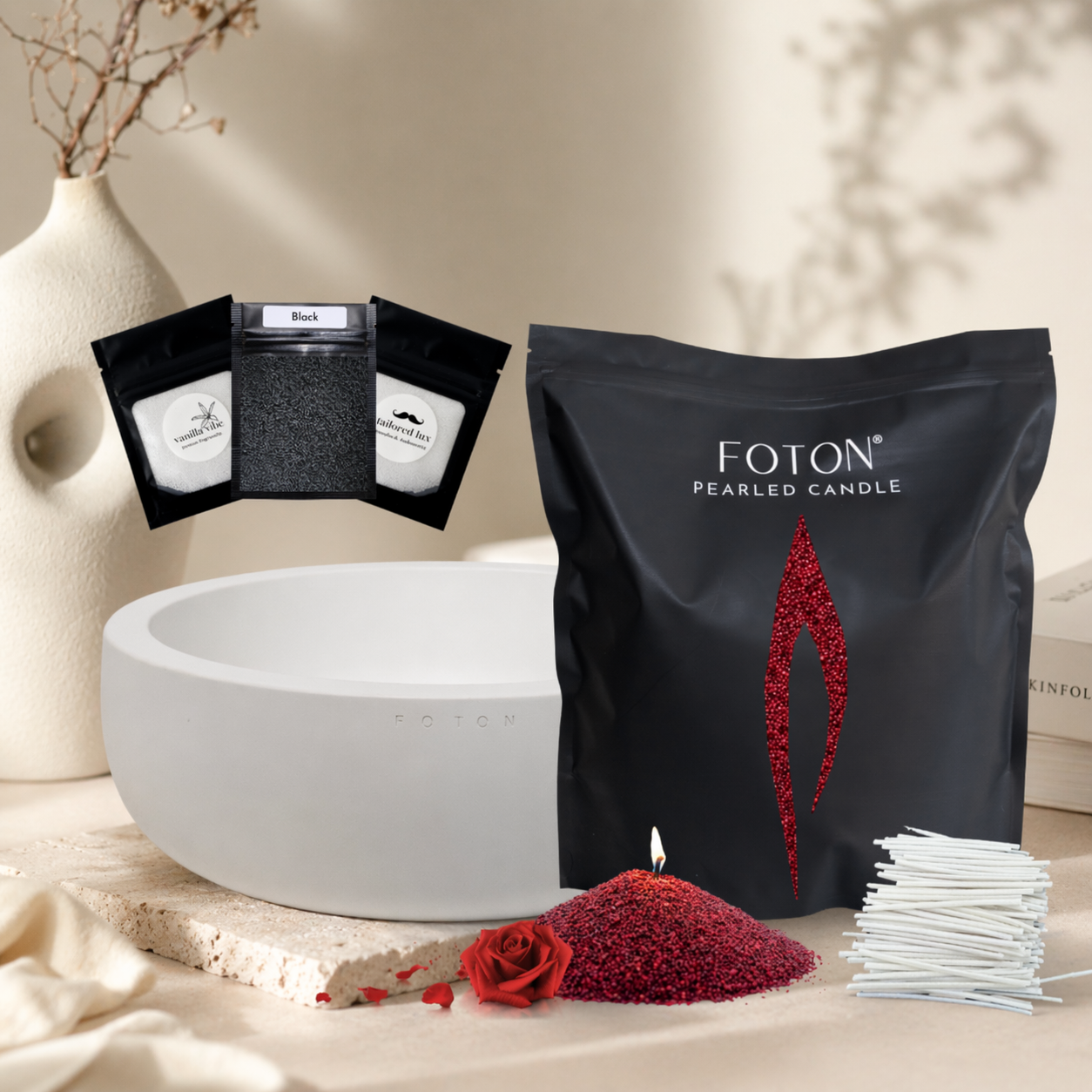 A refined product display featuring a Foton pearled candle gift set with a bold, romantic aesthetic. The scene includes a Grande bag filled with maroon pearls, a matching pile of maroon pearls with a lit wick, and a sleek white Luxe vessel ready for use. Accompanied by cotton wicks and sample scent pouches, the setup is styled with a red rose accent and neutral décor, creating an elegant, gift-ready presentation with a luxurious and slightly dramatic feel.