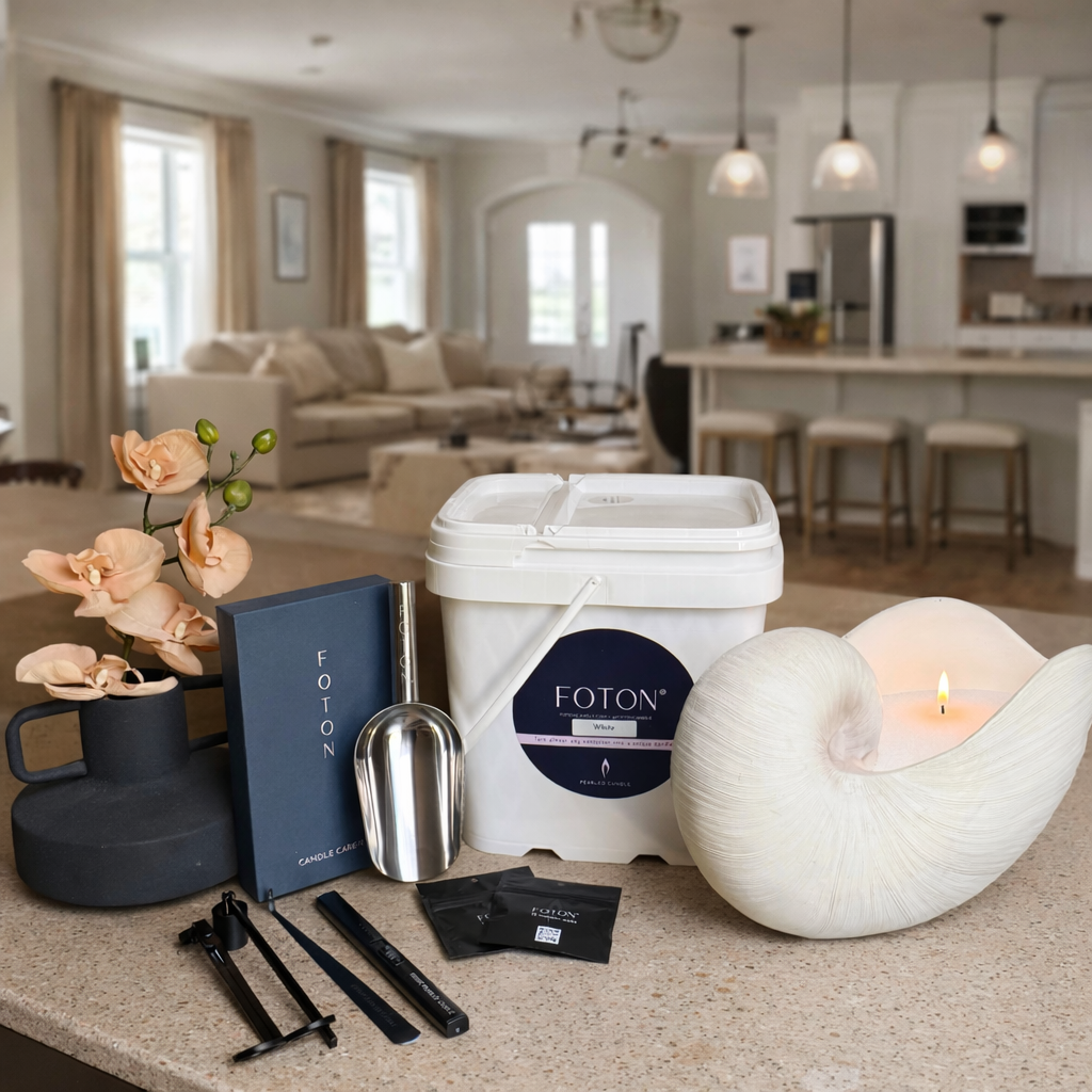 Lifestyle product image showcasing a complete Foton candle setup, featuring an XL-Kit (144oz) container of pearled wax, candle care tools, scent samples, and a sculptural candle vessel with a lit flame. The arrangement highlights the full premium kit in a bright, elegant home interior, emphasizing both functionality and elevated home décor.