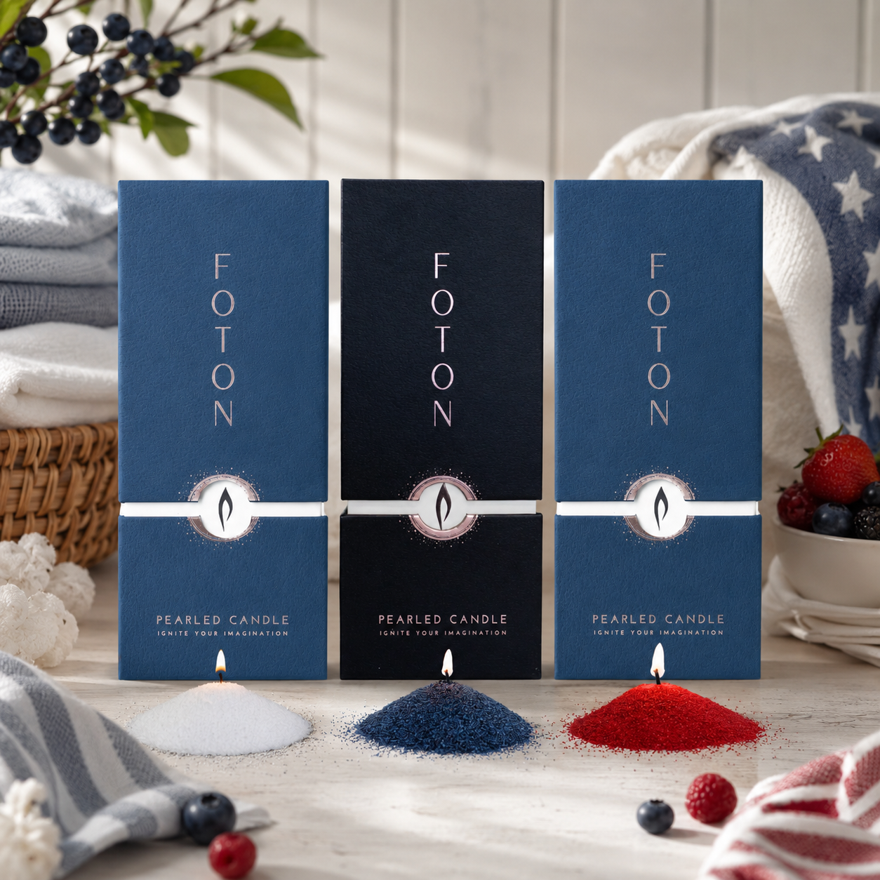 Patriotic-themed product display featuring three Foton pearled candle boxes in white, navy, and red color variations surrounded by berries, blankets, and decorative fabrics, with matching piles of candle pearls lit in front of each box.